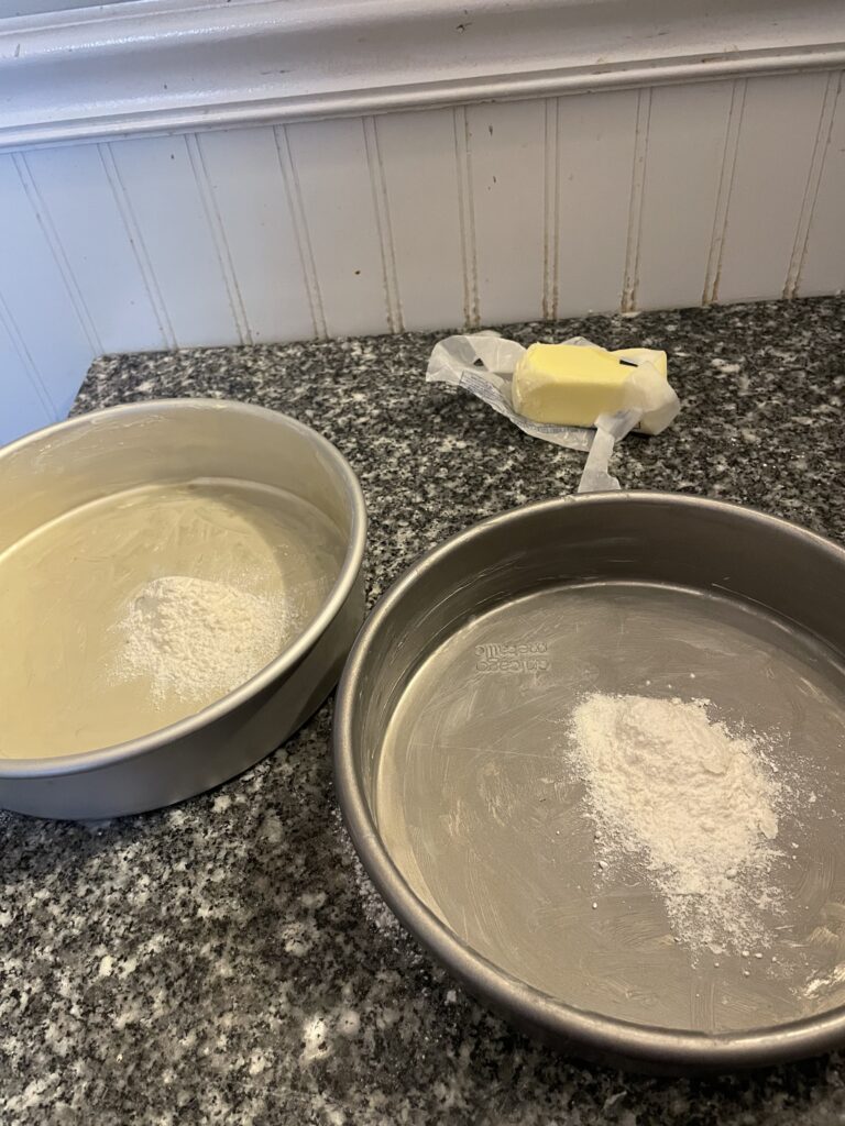 two greased round pans with a small bit of flour in the middle of each